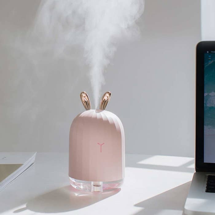 The small humidifier with light pink body and clear bottom and pink metallic ears on top and a small nose on the front.
