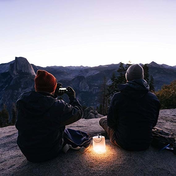 people sitting on mountain at dusk with lamp lit up