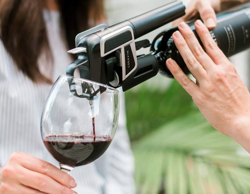 person pouring wine from bottle with wine preserver attached to spout