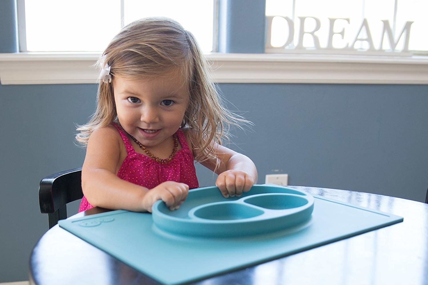 toddler sitting at table with their hands on the dinner plate/place mat that&#x27;s suctioned to the table