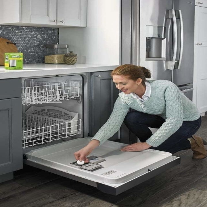 model puts small white tablet into machine