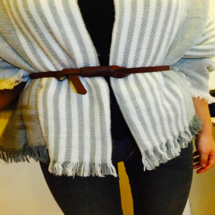 A reviewer wearing the knotted skinny belt in brown over a sweater