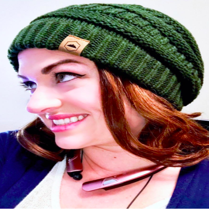 A reviewer wearing the green cable knit beanie