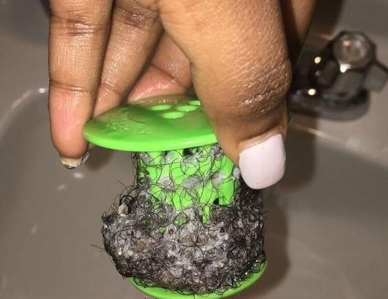 a reviewer holding a green tubshroom full of hair