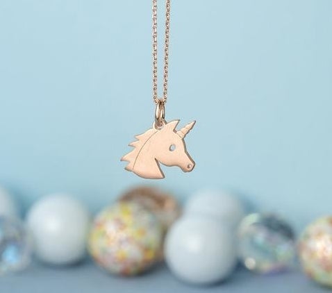A rose gold unicorn head charm on a chain