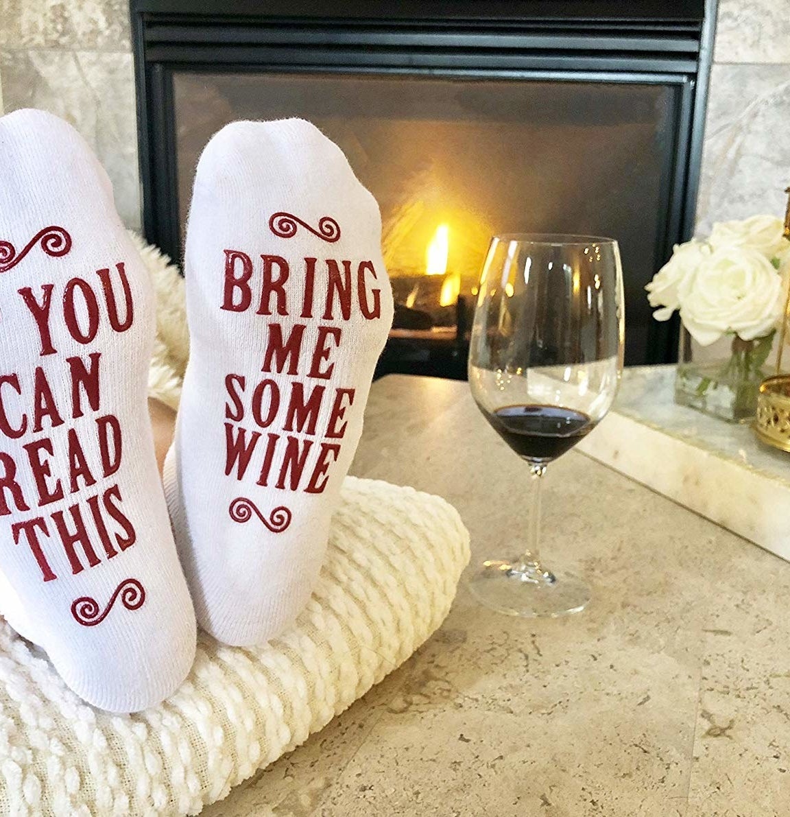 Person with feet up wearing socks that say on the sole &quot;If you can read this bring me some wine&quot; 