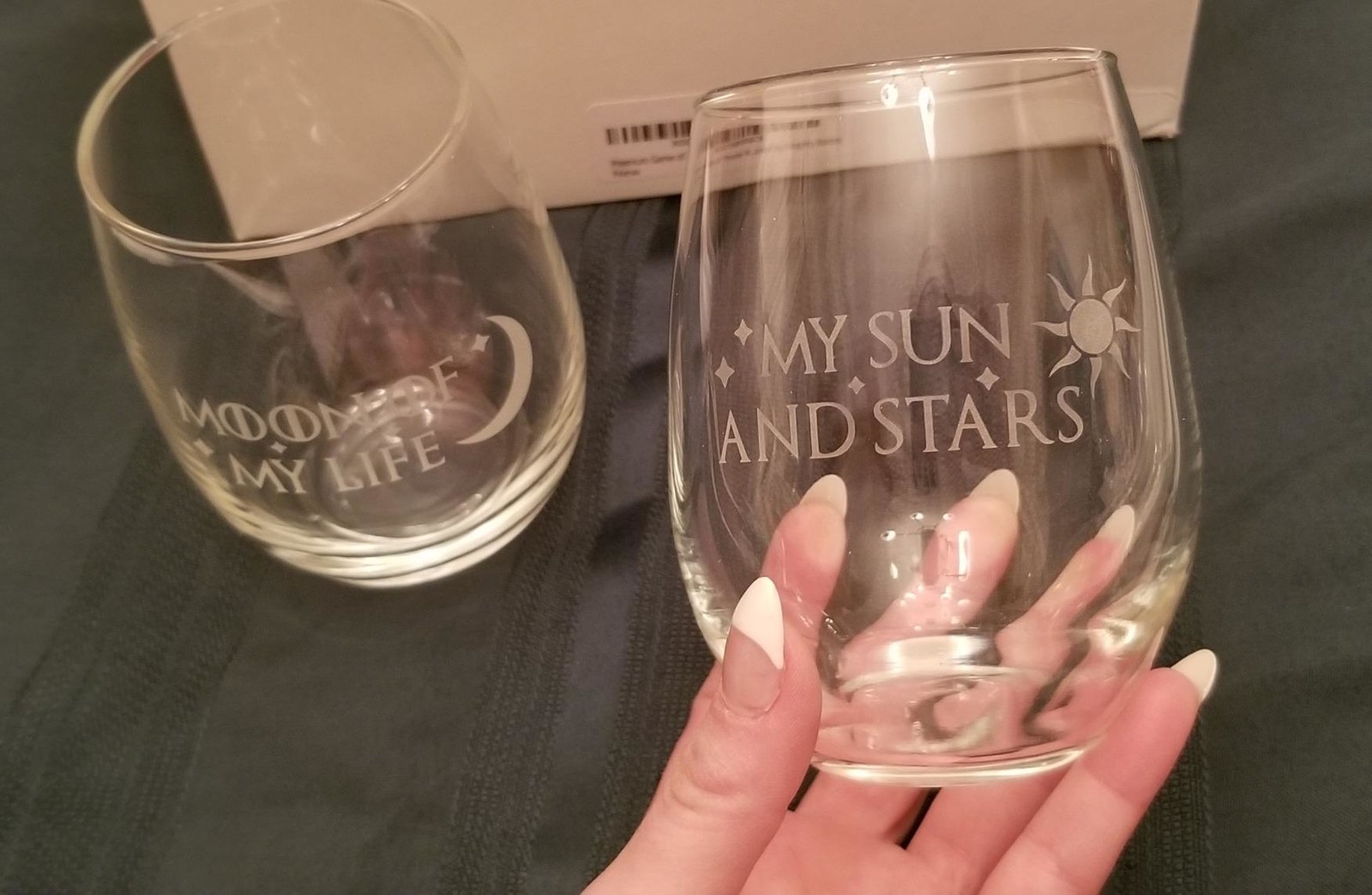 reviewer holding wine glasses that say &quot;moon of my life&quot; and &quot;my sun and stars&quot;
