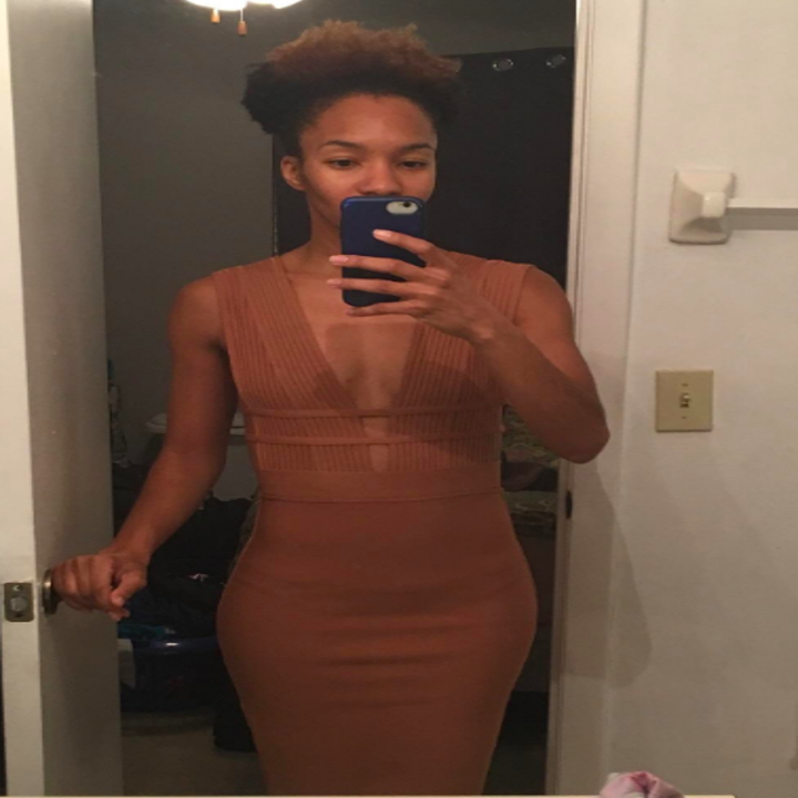 A reviewer wearing the sleeveless, plunging neckline dress in brown