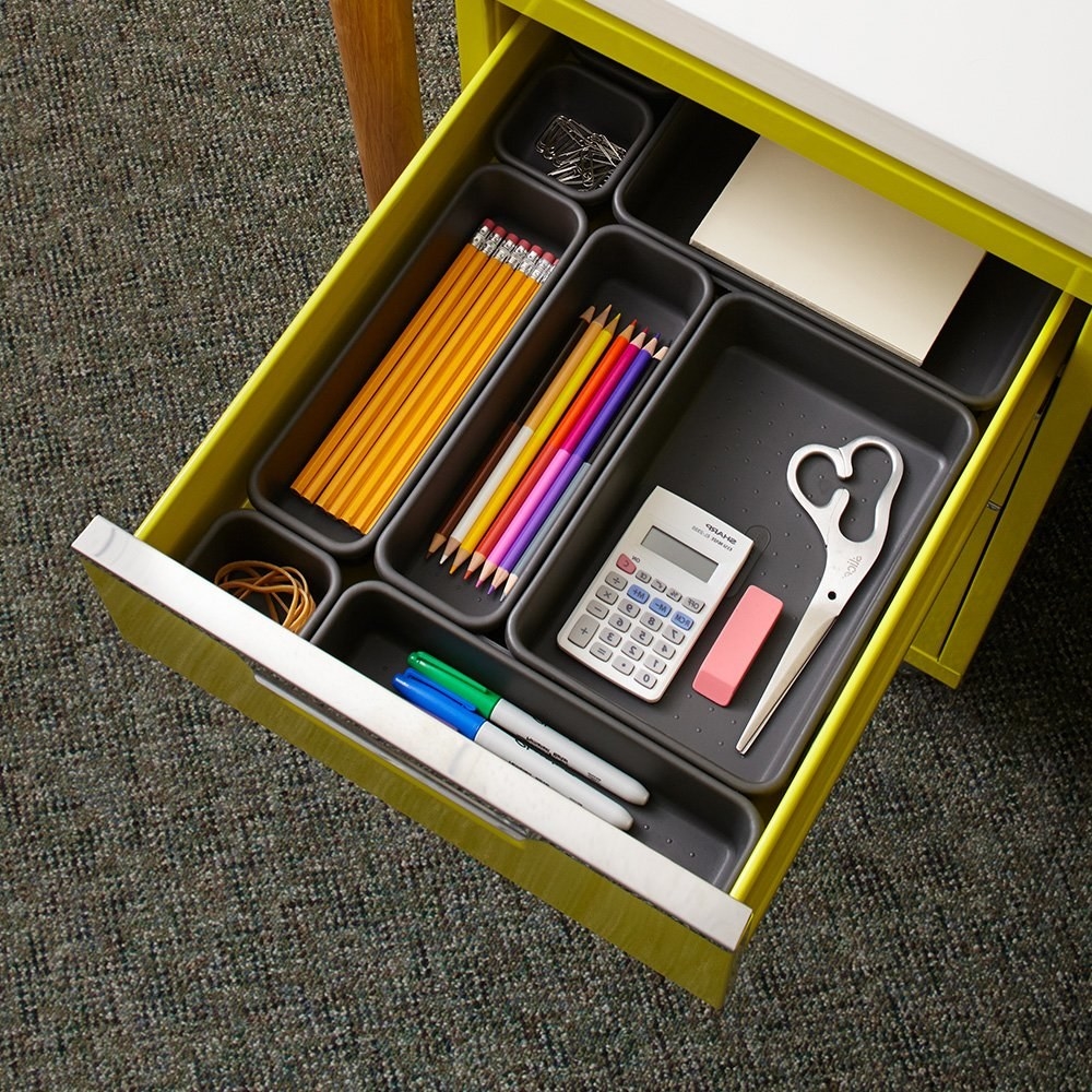 office drawer with seven different-sized organizers each holding pencils, color pencils, sharpies, and other supplies