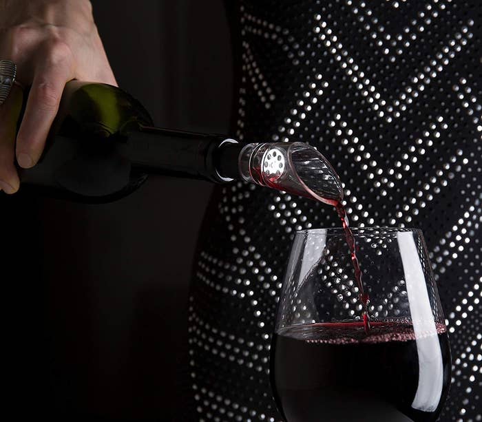 person pouring wine into glass using aerator
