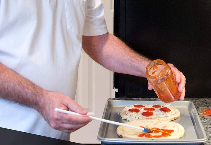 Spatty being used to apply tomato sauce to pizza crust 