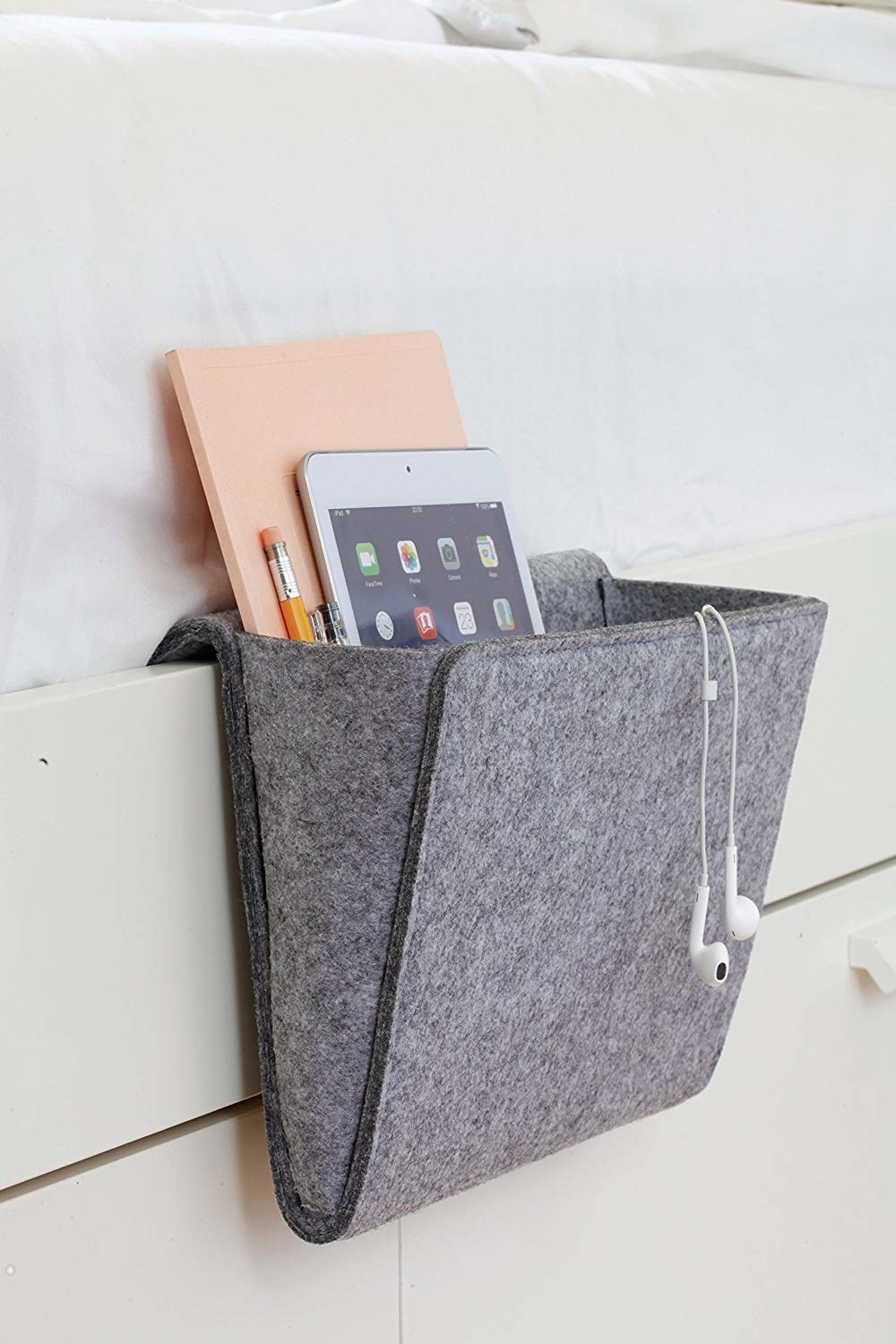 Felt bedside caddy containing headphones, tablet, and notebook