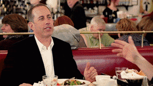 Jerry Seinfeld looking at the check in a restaurant in shock