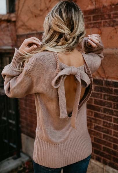 A model in the light brown sweater picutred to show off the open back with a tie at the top