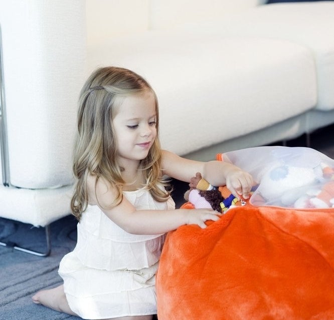 A small child stuffing the bean bag with their toys