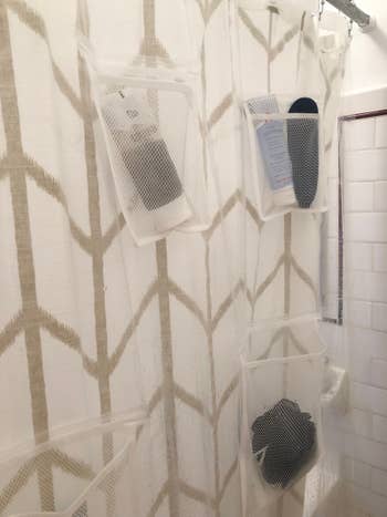 shower liner with mesh storage pockets on it filled with toiletries