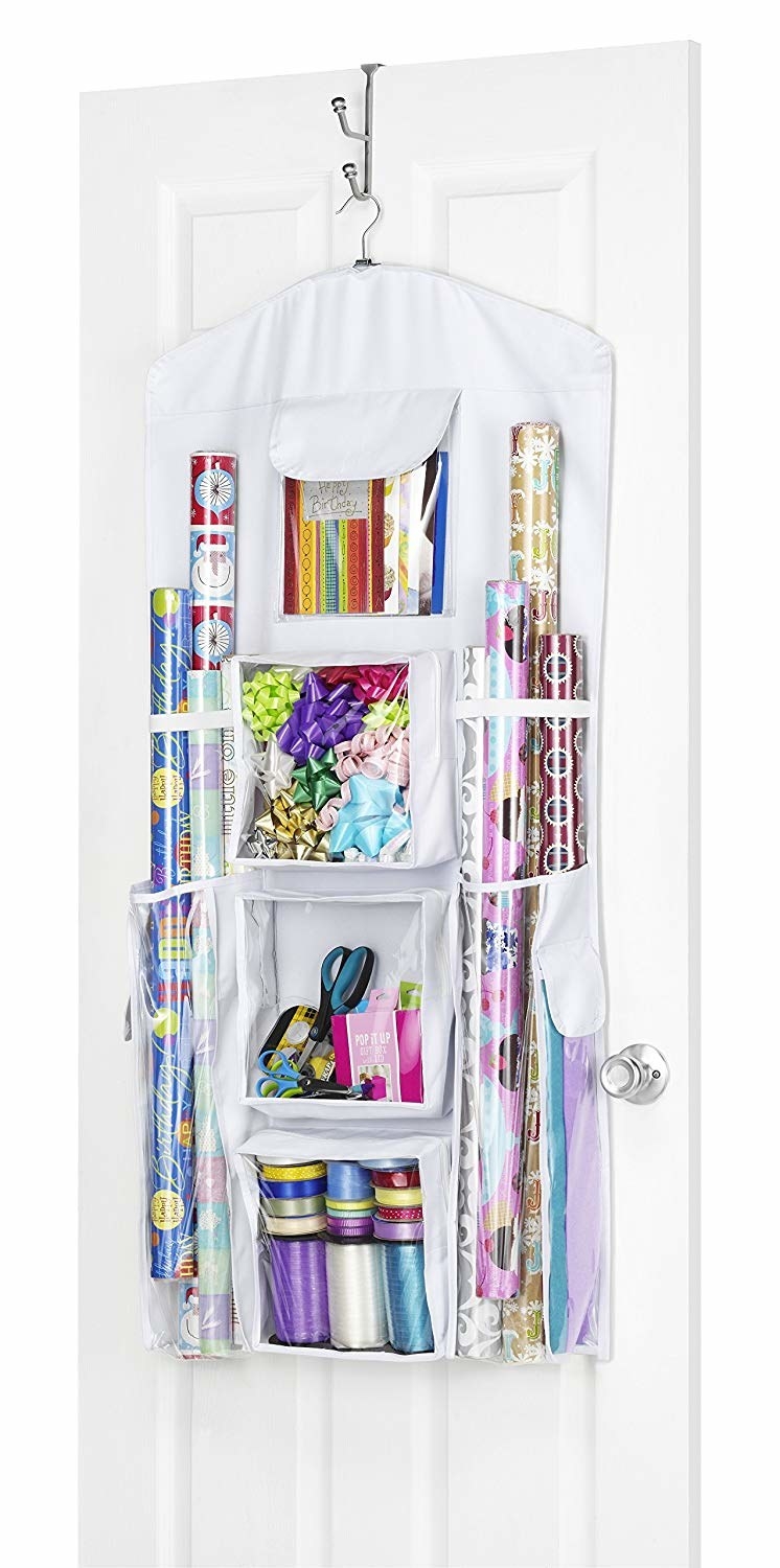 The over-the-door organizer hanging filled with wrapping paper, bows, and ribbon