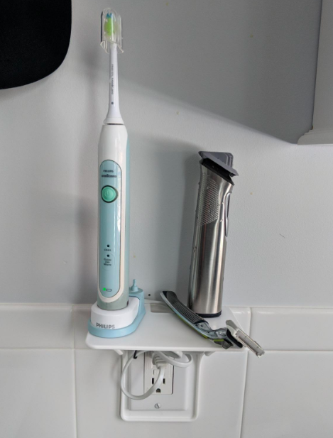 A reviewer&#x27;s photo of the shelf holding an electric toothbrush and razor