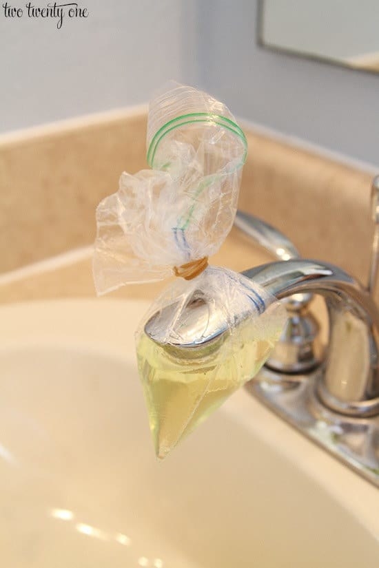 blogger&#x27;s bathroom sink with baggie full of vinegar tied over it using a rubber band