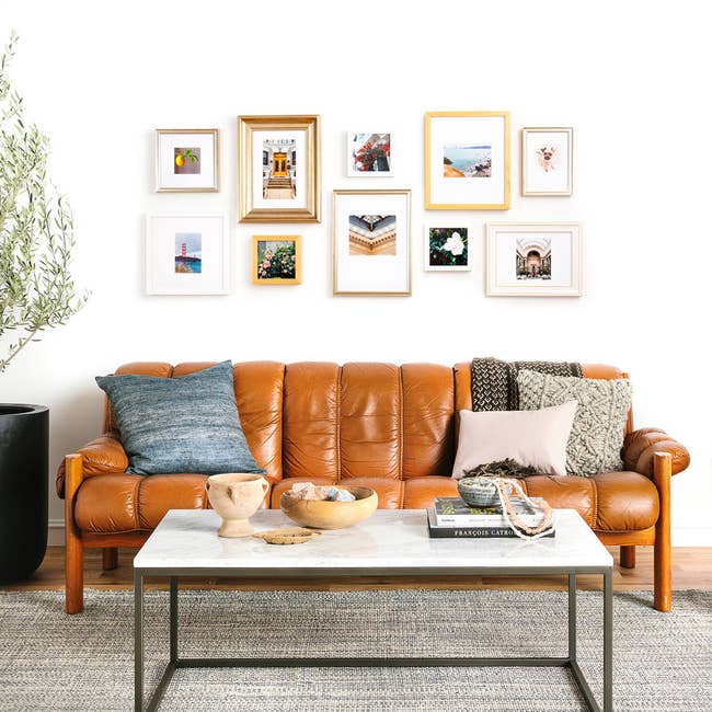 living room couch with gallery wall of pictures hanging above it on the wall 