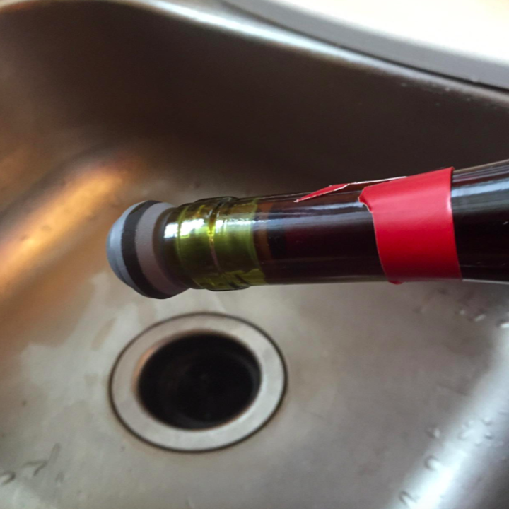 a reviewer photo with the wine bottle tilted down to demonstrate that the wine vacuum stopper works because no wine is leaking outside of it 