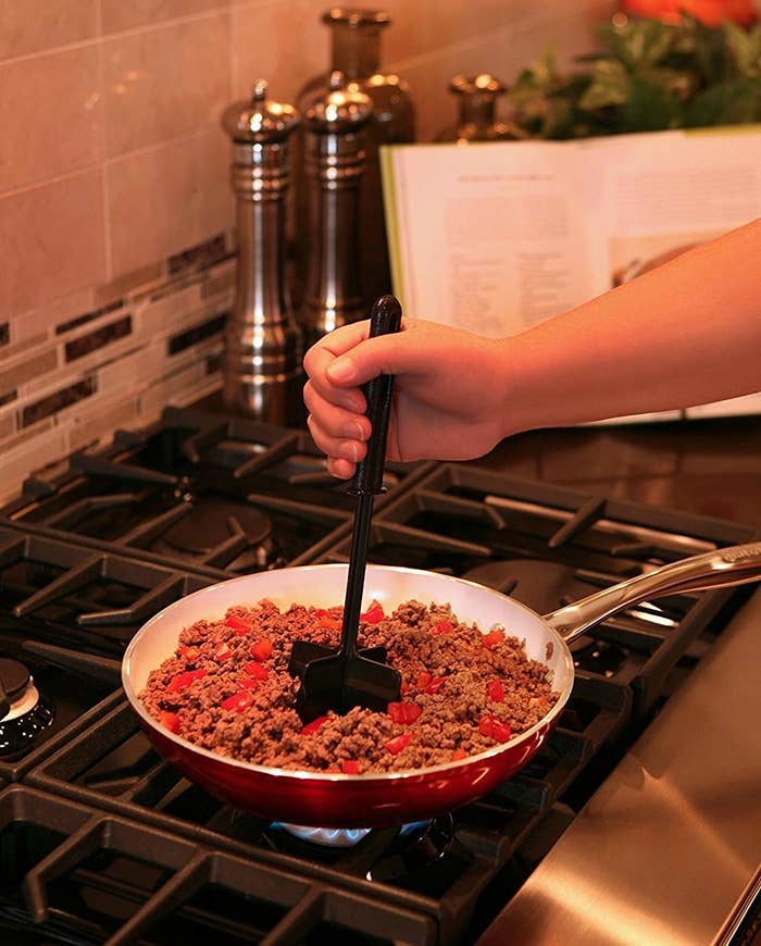 the tool with four horizontal blades mixing up ground meat in a pan
