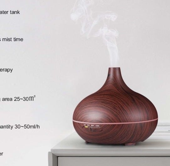 The diffuser in brown with a wood-like pattern sitting on a table releasing steam into the air