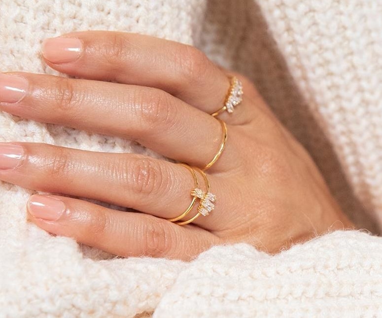a hand wearing the dainty gold rings