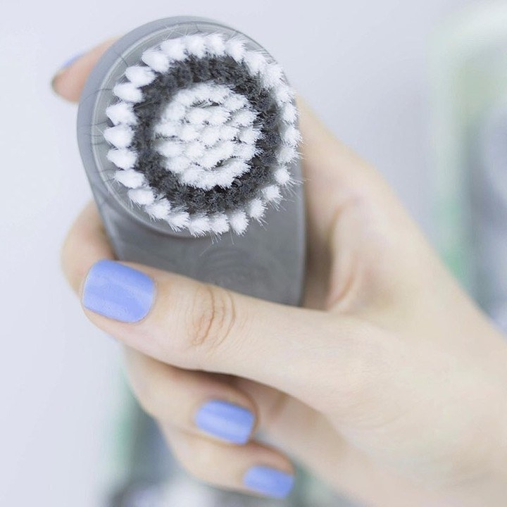 Hand holding the facial-cleansing brush 
