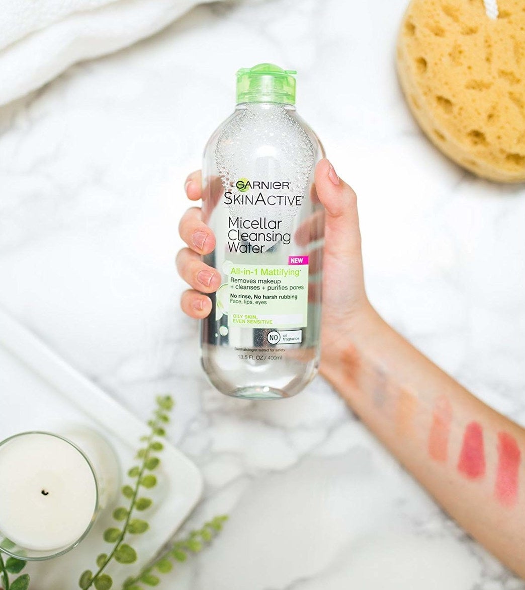 Hand holding the micellar water with marble table background