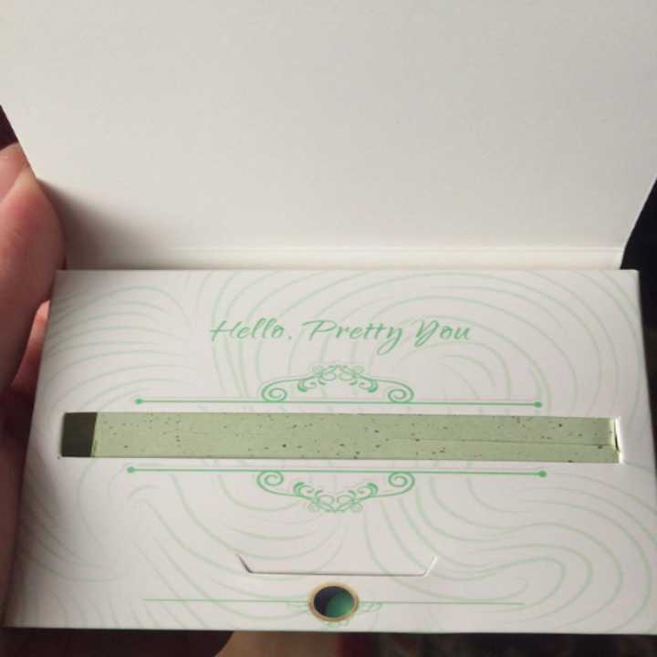 a reviewer holding the pack of oil-absorbing tissues