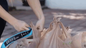 Model using the carrier to connect all the grocery bags and hoist them over their shoulder 