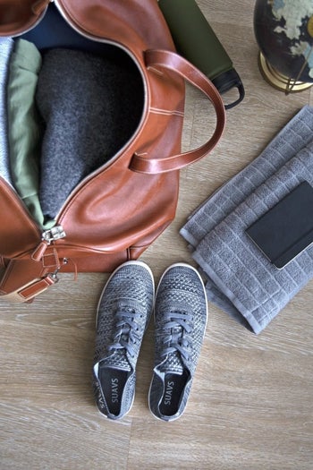 pair of gray sneakers sitting next to travel bag