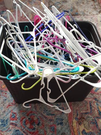 Reviewer photo of a trash can full of messy, tangled plastic hangers