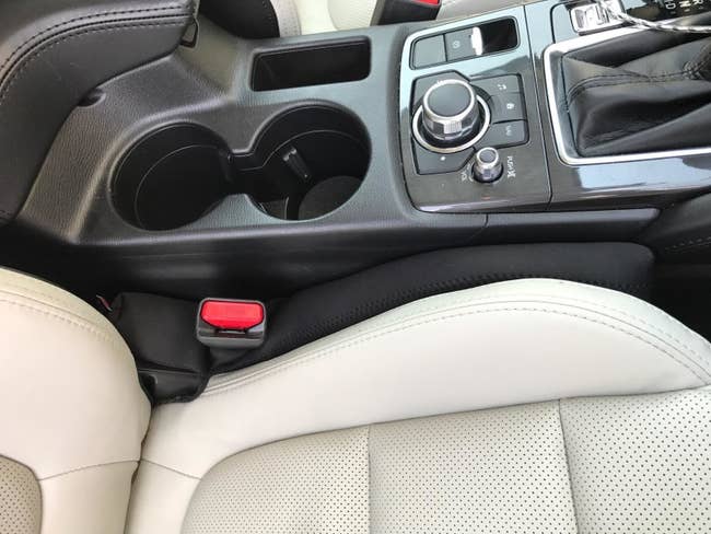 Reviewer's black gap filler in between the seat and console in a car