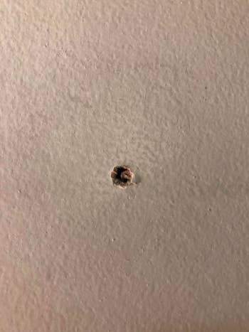 A reviewer showing a large hole in their wall