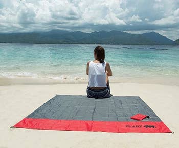 blanket spread out at beach and person sitting on it