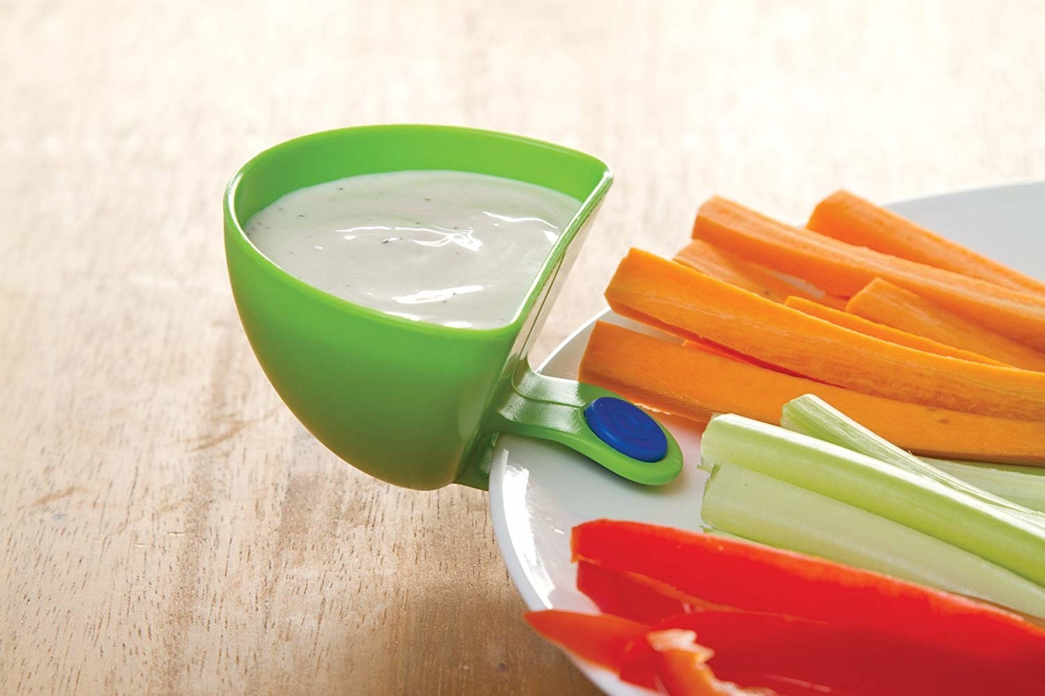 dip clip filled with ranch dressing and securtely attached to a dinner plat that has strips of veggies for snacking