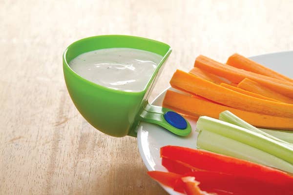 dip clip filled with ranch dressing and securtely attached to a dinner plat that has strips of veggies for snacking