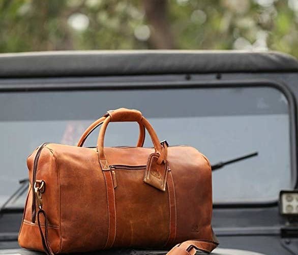 the leather weekender bag sitting on top of a Jeep