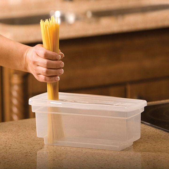 a hand holding spaghetti over the container