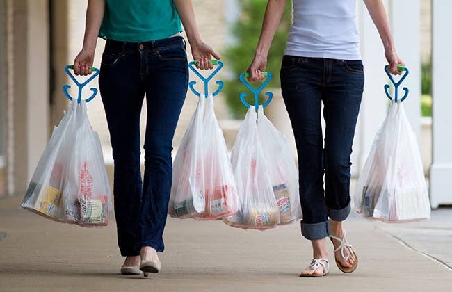 two models walking with grocery bags in each hand held by the bag carriers