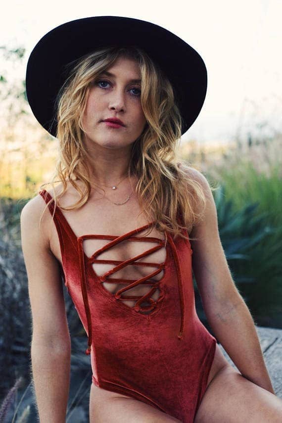 model wearing the red velvet one piece with criss-crossed straps across the chest