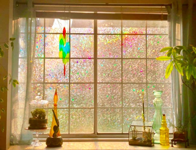 a reviewer's photo of the privacy window film with colorful light streaming through a large window 