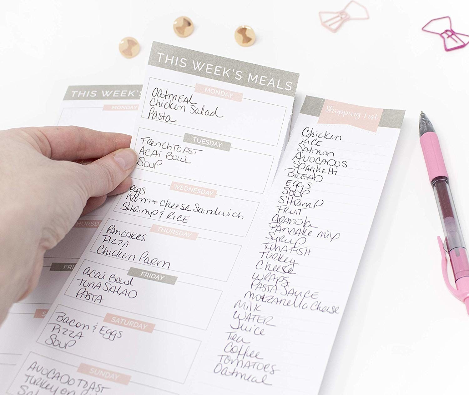A model&#x27;s hand ripping off a filled-out page of the meal plan notepad 