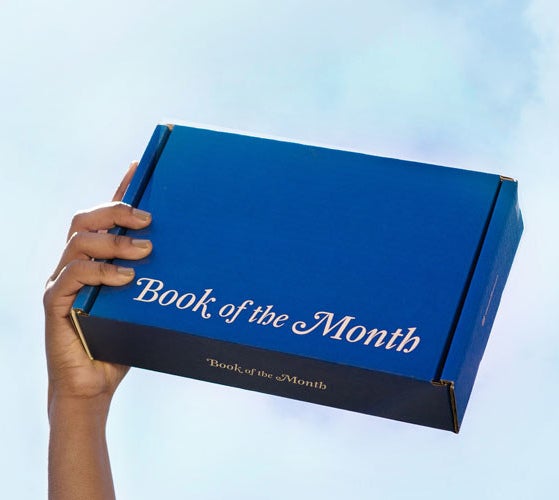 Hand holding book of the month box. 