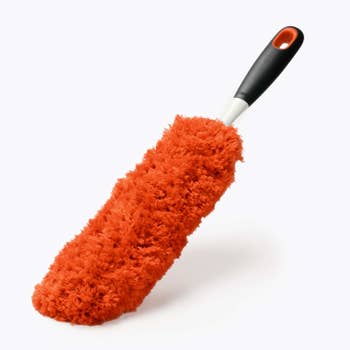 The red, fluffy, oval-shaped long duster with a black and white plastic handle
