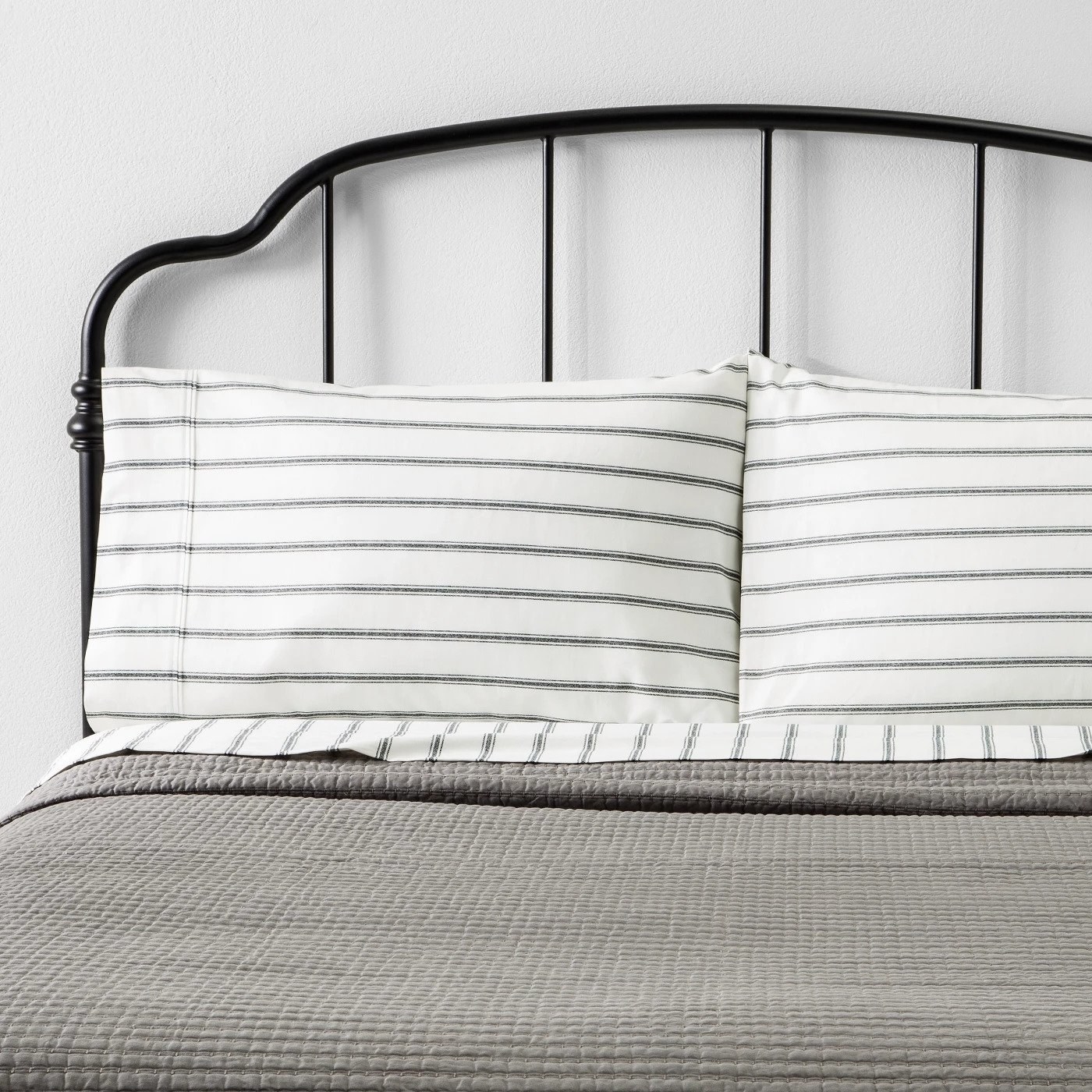 a bed made with the gray and white striped sheets