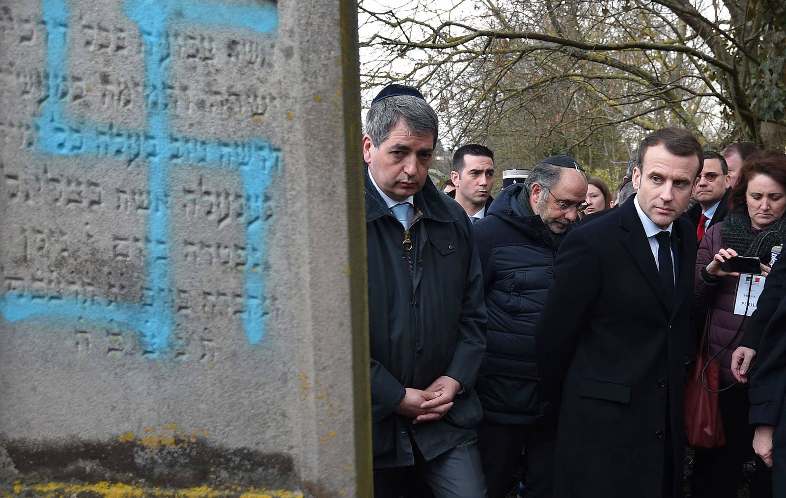 French President Emmanuel Macron looks at a grave vandalized with a swastika during a visit at the Jewish cemetery in Quatzenheim, France, on Feb. 19.