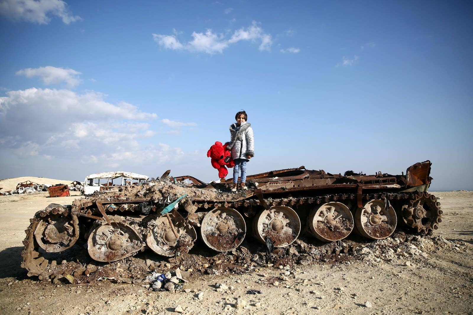 Rawan, an 11-year-old Syrian girl, poses on a destroyed tank with her stuffed bear near the village of Yazi Bagh on Feb. 19.